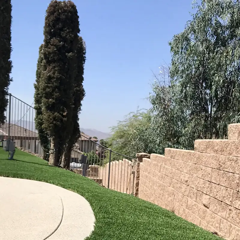 Hillside synthetic turf installation along a retaining wall